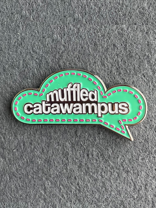 A teal thought bubble pin with white text that reads "Muffled Catawampus"