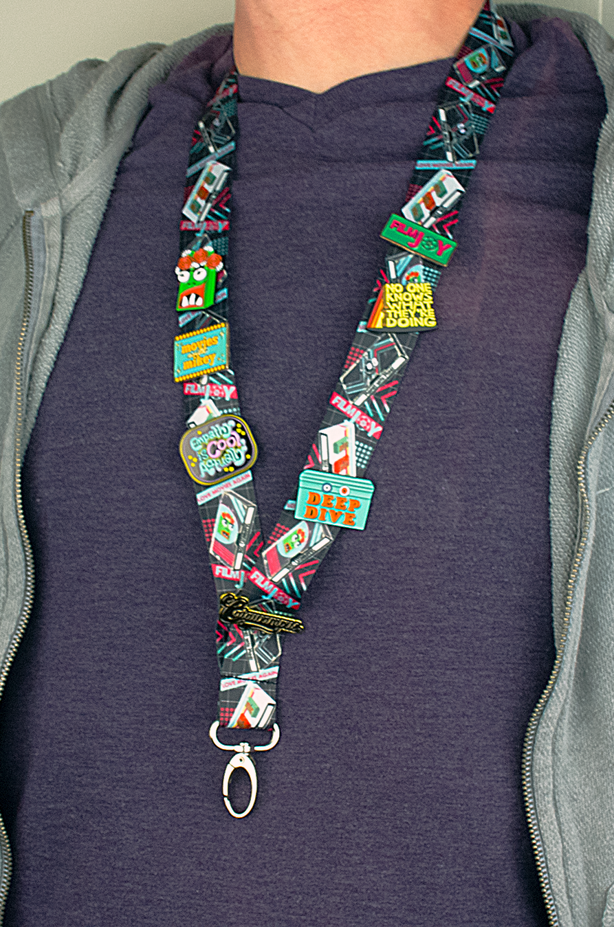 A Lanyard with several enamel pins attached for size reference. 